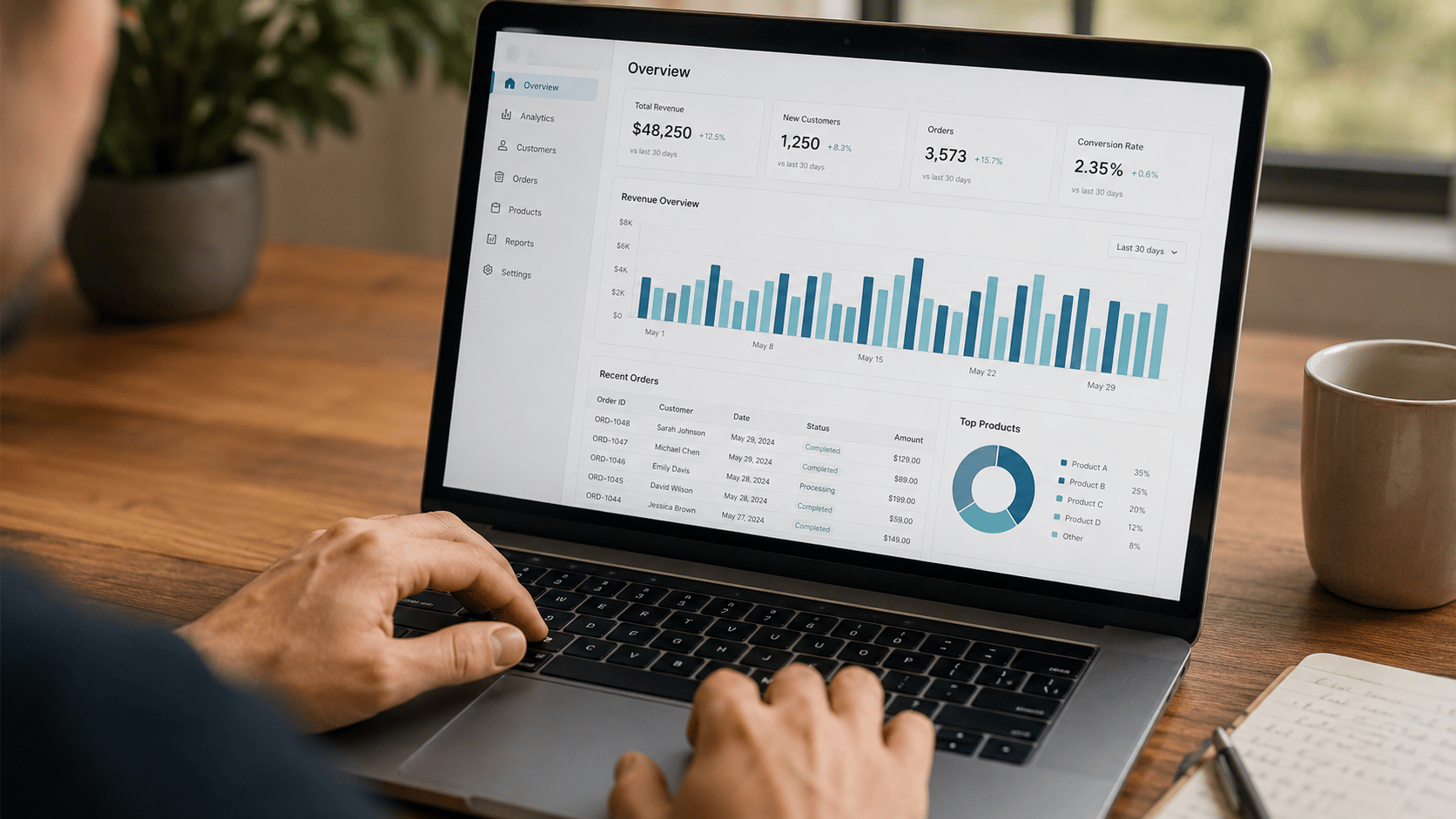 Mains sur un ordinateur portable consultant un tableau de bord d'analytics et de commandes.